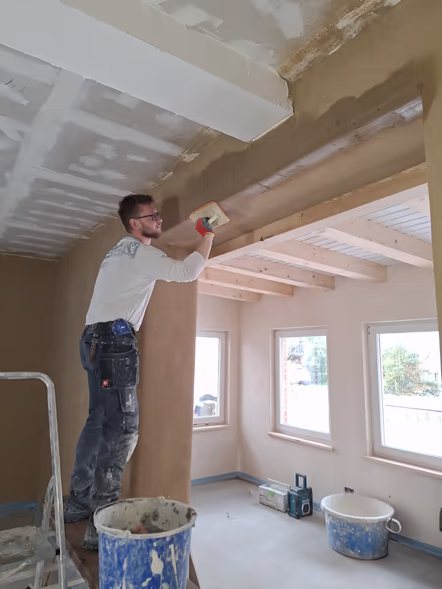 Junger Bauhandwerker verputzt eine Innenwand in einem Neubau in Görlitz nahe Dresden